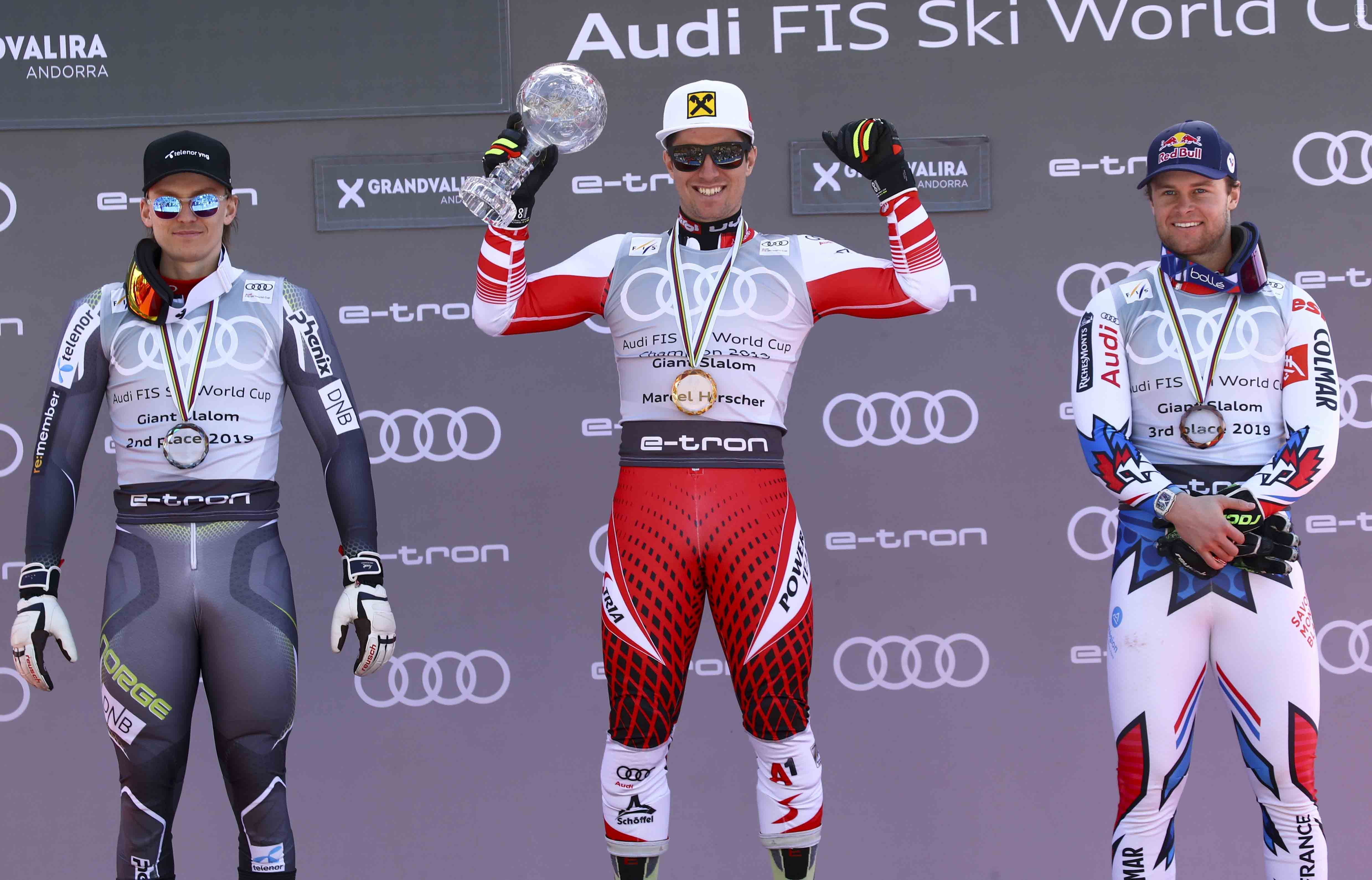 Rakúsky lyžiar Marcel Hirscher (uprostred) pózuje na pódiu s medailou a malým glóbusom po jeho výhre obrovského slalomu mužov Svetového pohára v alpskom lyžovaní v Soldeu 16. marca 2019. Vľavo druhý Nór Henrik Kristoffersen a vpravo tretí Francúz Alexis Pinturault.